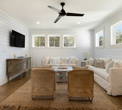 Sink into plush white sofas in this bright living room where shiplap walls and natural light create your perfect retreat space.