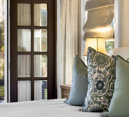 Sink into plush pillows where morning light dances through elegant French doors, creating your perfect sanctuary for rest and relaxation.