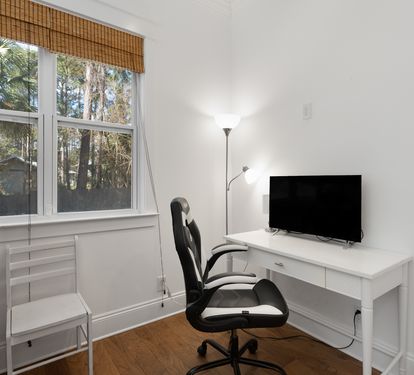 Your bright workspace features a sleek desk, comfortable chair, and TV - perfect for remote work with peaceful garden views.