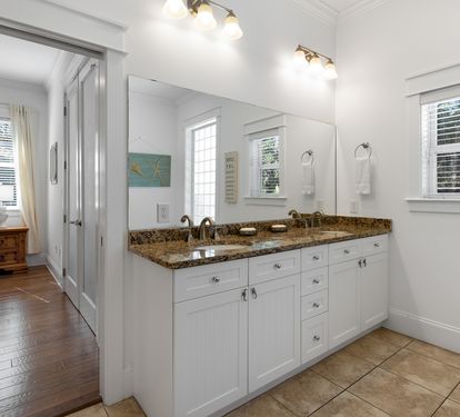 Refresh in your spacious bathroom featuring dual sinks, granite counters, and bright natural light from large windows.
