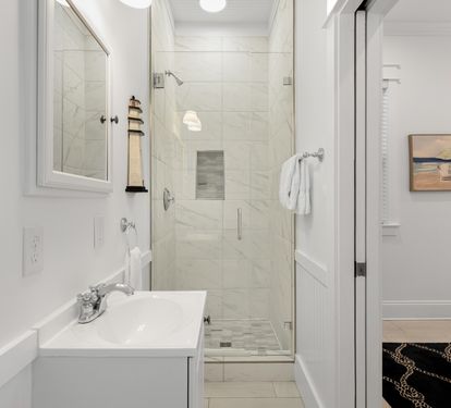 Step into your pristine bathroom with marble shower, fresh towels, and coastal artwork creating a spa-like retreat.