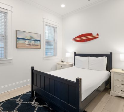 Rest easy in your coastal bedroom with crisp white linens and cheerful surf-themed decor that captures beachside charm.