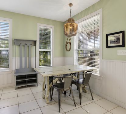 Gather around your bright dining nook with farmhouse charm, featuring a rustic table surrounded by windows that fill the space with natural light.