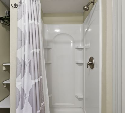 Step into your private shower sanctuary with fresh white linens, convenient corner shelves, and everything ready for your refreshing morning routine.