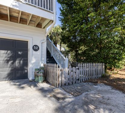 Charming coastal property entrance with convenient garage parking and natural landscaping in a peaceful residential setting.