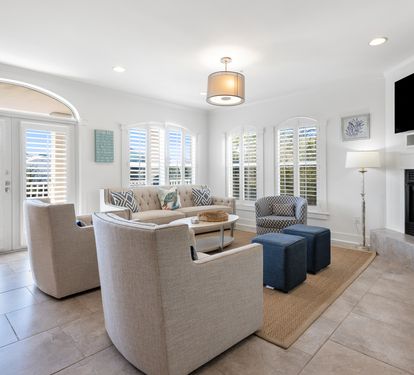 Relax in your bright living room with cozy fireplace, comfortable seating, and peaceful shuttered windows creating the perfect retreat.