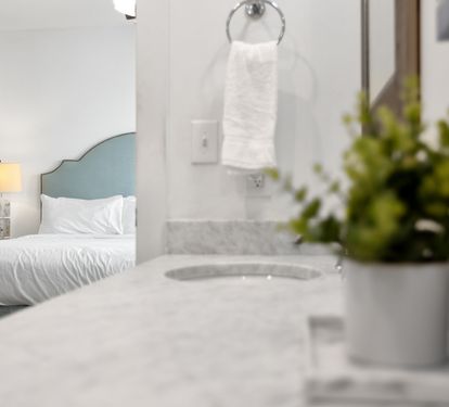 Unwind in your serene bedroom sanctuary where marble textures meet soft linens and fresh greenery creates a peaceful retreat.