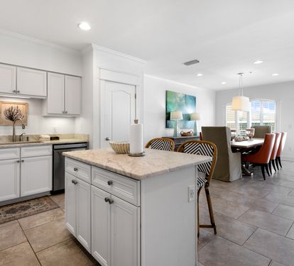 Your spacious kitchen flows seamlessly into the dining area, featuring elegant white cabinetry, modern appliances, and a convenient island for meal prep and casual dining.