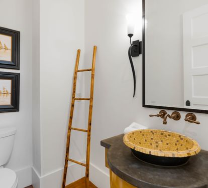 Step into your stylishly designed powder room featuring a striking woven vessel sink and warm brass fixtures that create an inviting, spa-like atmosphere.