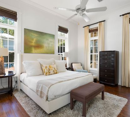 Unwind in your serene master bedroom with crisp linens, original hardwood floors, and peaceful garden views through charming French doors.