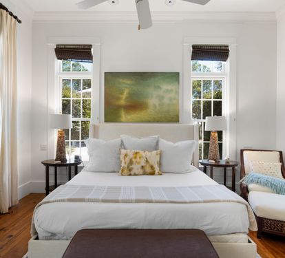 Your elegant bedroom features crisp white linens, warm hardwood floors, and natural light streaming through multiple windows for peaceful mornings.