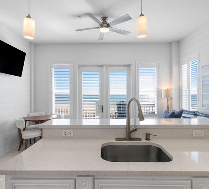 Your bright kitchen features sleek countertops and stunning ocean views through expansive windows, perfect for morning coffee with sea breezes.