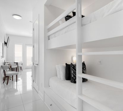 Your modern white bunk bed sanctuary offers space-saving comfort with built-in storage and individual reading lights for peaceful nights.