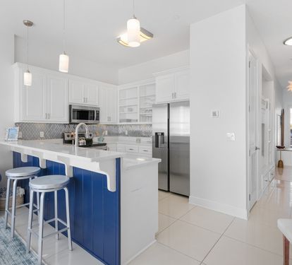 Your fully-equipped kitchen with sleek white cabinets and vibrant blue island awaits your culinary adventures.
