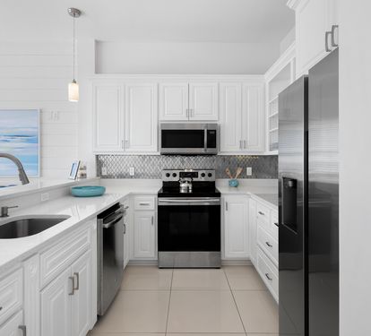 Your modern kitchen awaits with gleaming countertops, stainless appliances, and ocean artwork that sets a coastal mood for preparing meals.