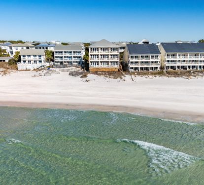 Gulf front property complex with direct access to pristine white sand and crystal-clear emerald waters.