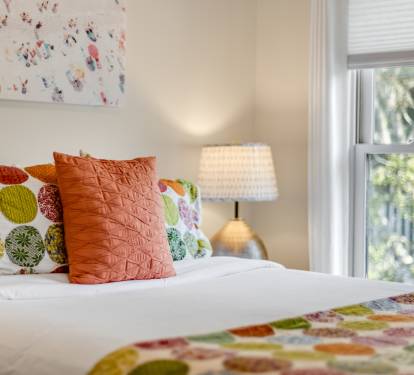 Sink into this cheerfully decorated bedroom with colorful pillows, soft lighting, and leafy garden views through your window.