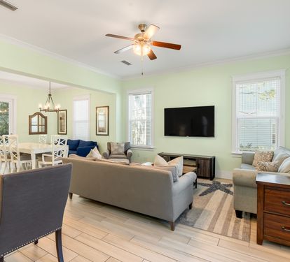 Relax in your spacious open-concept living area with comfortable seating, modern TV, and charming coastal touches throughout.