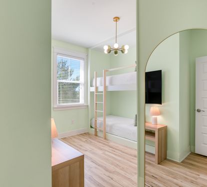 Your kids will love this cheerful bunk room with soft green walls, cozy lighting, and space to play and rest.
