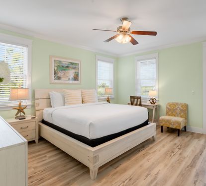 Unwind in your serene bedroom sanctuary with soft mint walls, elegant wood furnishings, and coastal accents that invite peaceful rest.