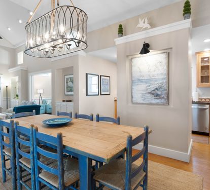 Gather around your beautiful coastal dining table where blue chairs invite memorable meals beneath the statement chandelier.