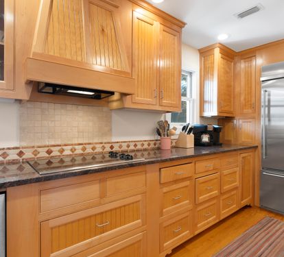 Prepare delicious meals in this elegant kitchen featuring warm wood cabinetry, granite countertops, and modern appliances for your culinary adventures.