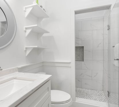 Pristine marble bathroom featuring a luxurious walk-in shower and elegant built-in shelving for your comfort.