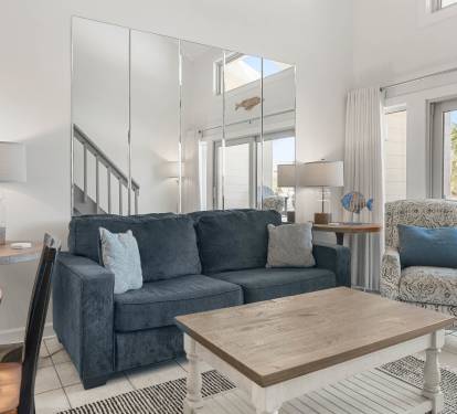 Sink into coastal comfort in your bright living space with stylish furnishings and gentle natural light streaming through large windows.