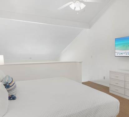 Drift off in your peaceful attic bedroom, where crisp white linens and coastal artwork create a serene seaside retreat.