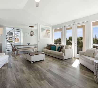 Sink into plush white sofas bathed in natural light, where floor-to-ceiling windows frame peaceful treetop views for your perfect getaway.