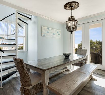 Gather around this beautiful farmhouse dining table where natural light streams through coastal windows, creating the perfect space for memorable meals with family.