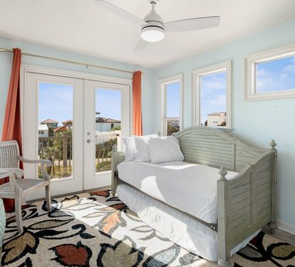 Relax in your bright coastal retreat with serene blue walls, comfy daybed, and French doors opening to your private balcony.