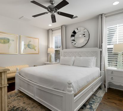 Rest peacefully in this elegant bedroom featuring a plush queen bed, calming sea turtle artwork, and gentle ceiling fan for your comfort.