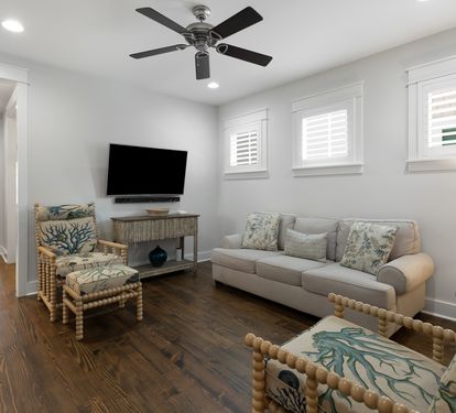Your bright living room features coastal-inspired seating, flat-screen TV, and ceiling fan for perfect relaxation after beach days.