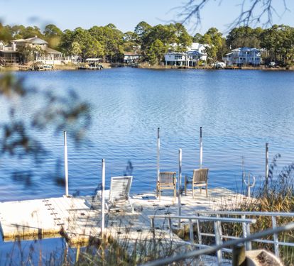 Peaceful lakefront setting with waterfront homes dotting the tree-lined shore across calm blue waters.