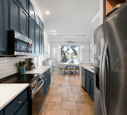 Cook memorable meals in your stylish galley kitchen, featuring sleek navy cabinets, stainless steel appliances, and bright subway tile backsplash.