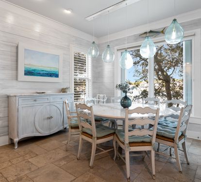 Gather around this charming dining table where coastal breezes flow through windows and sea-glass pendant lights create the perfect ambiance for your meals.