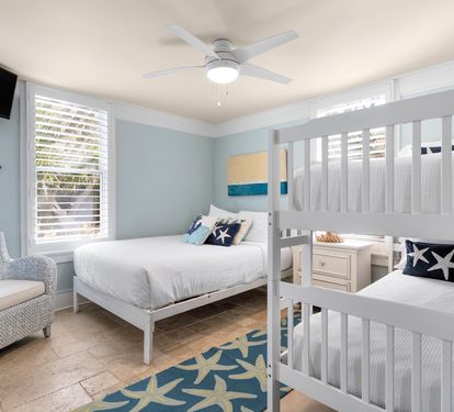 Your coastal-themed bedroom features crisp white bunk beds and nautical decor, creating a serene retreat where ocean breezes flow through plantation shutters.