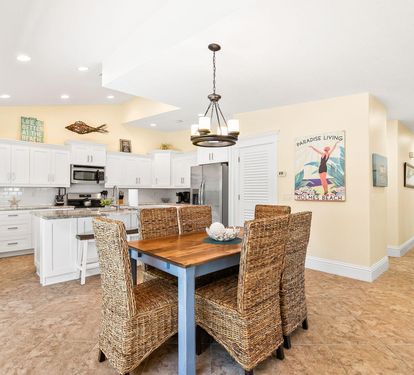 Wicker chairs and a rustic wood table make for a casual dining spot just off the fully renovated kitchen.