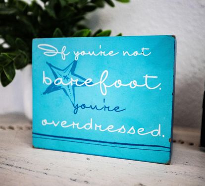 A playful "barefoot" sign captures the easygoing, beach-house feel throughout Coastal Cottage.