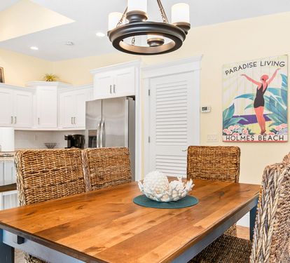 The wood dining table seats the whole group, with cheerful island-inspired artwork setting the tone.