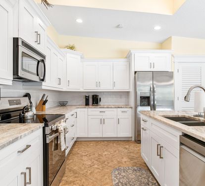 A wide view of the fully renovated kitchen — white cabinetry, stainless appliances, and granite counters throughout.