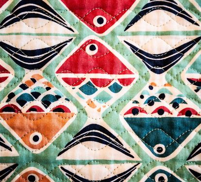 A colorful handmade quilt adds warmth and character to Coastal Cottage's beach-inspired decor.