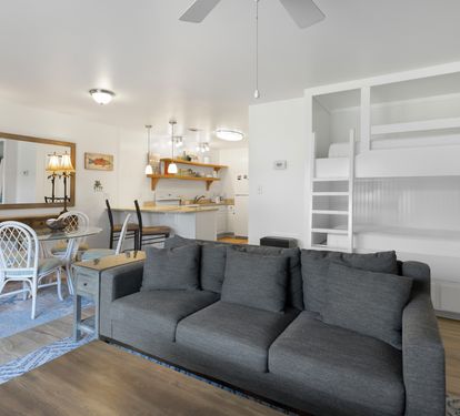 Relax on the plush gray sofa while kids enjoy built-in bunk beds. Open-concept design connects you to the kitchen and dining area.