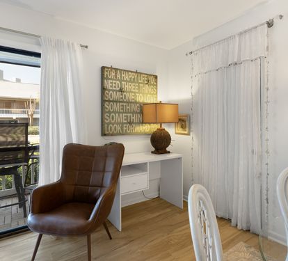 Settle into your bright workspace where inspirational art meets modern comfort, perfectly positioned by windows overlooking tropical palms.