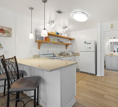Your fully equipped kitchen invites morning coffee at the breakfast bar, with modern appliances and charming coastal touches for home-cooked meals.