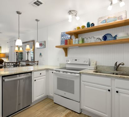Your bright kitchen features granite counters, stainless appliances, and charming open shelving with coastal touches for your perfect beach getaway.