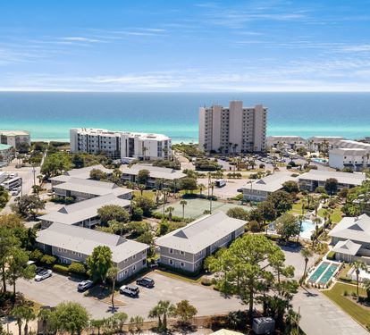 Aerial view of beachfront community with turquoise waters and white sand beaches just steps away.