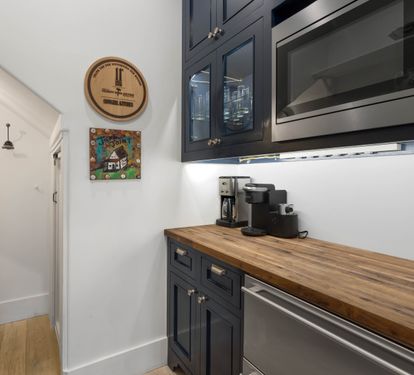 Your stylish kitchen features rich navy cabinetry, warm butcher-block counters, and premium stainless appliances ready for morning coffee.