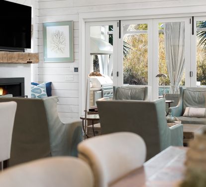 Relax in your bright living space with crackling fireplace, wall-mounted TV, and cozy seating overlooking tropical gardens.